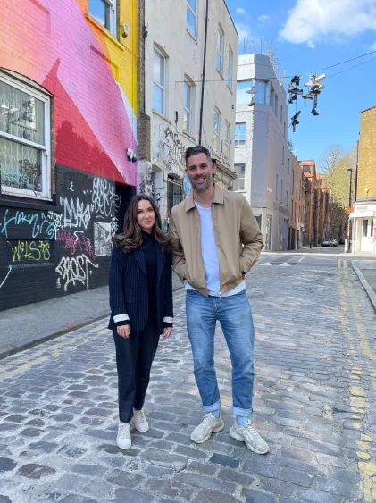 Brent and Jenna posing for a photo, with a city background